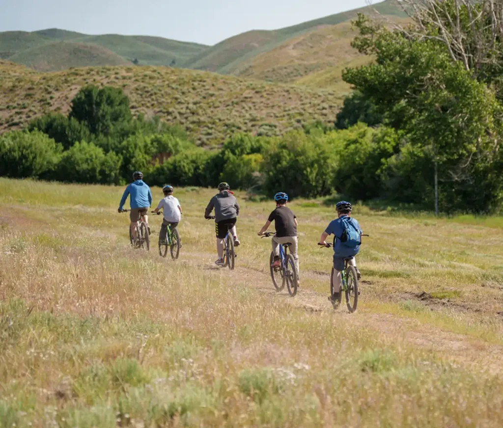 Group biking on scenic trails at Hidden Paradise Idaho — outdoor adventure and family recreation surrounded by rolling green hills.